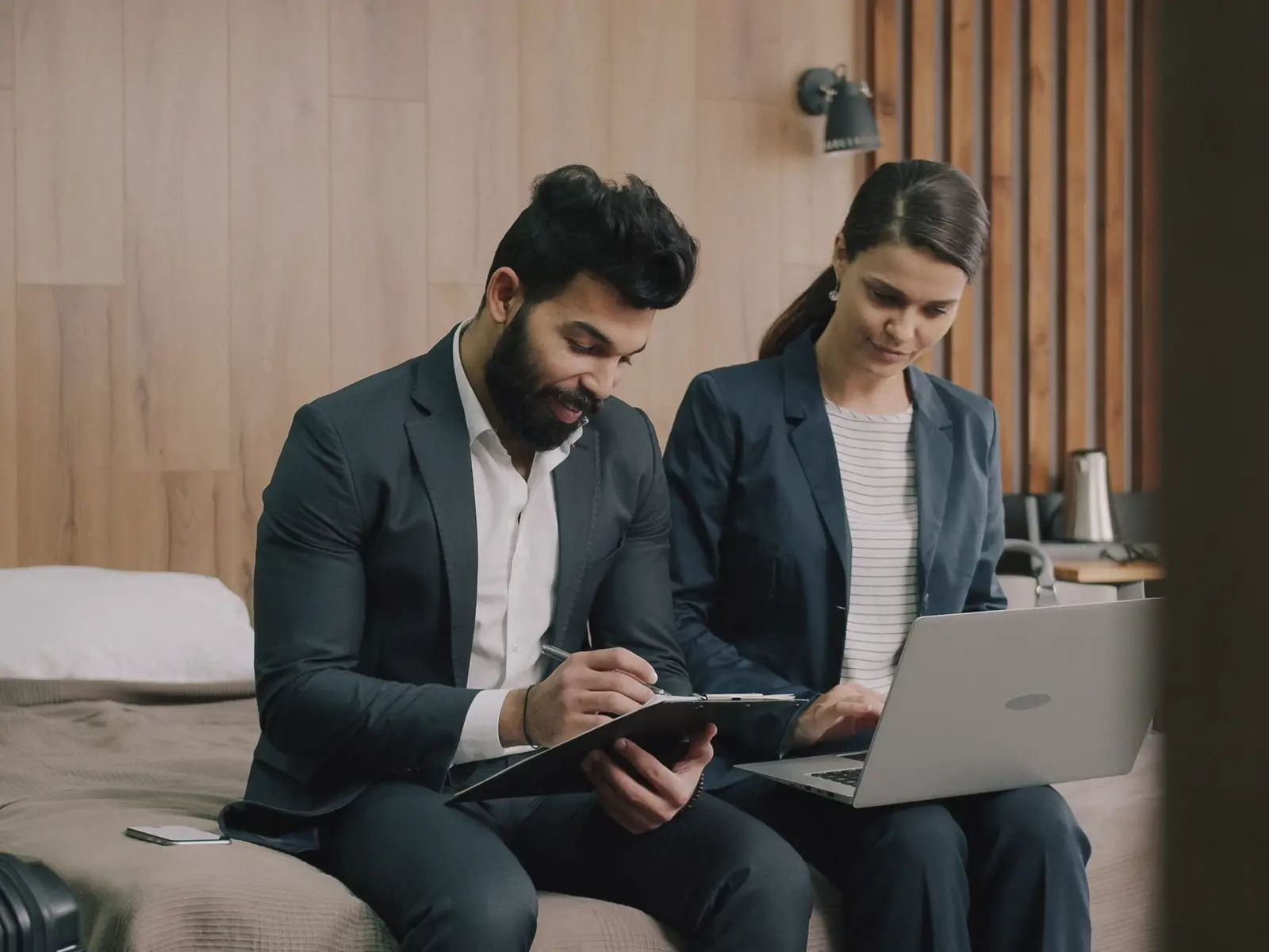 Two hotel managers planning together over a laptop and a clipboard