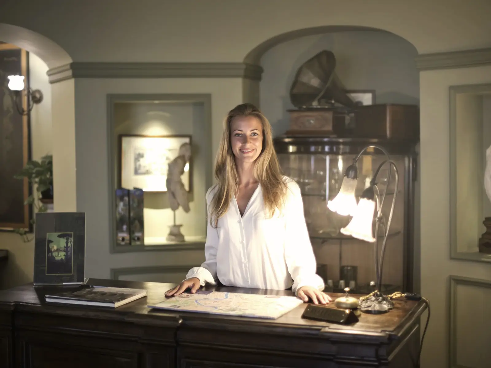 A smiling guest house owner standing at her reception desk